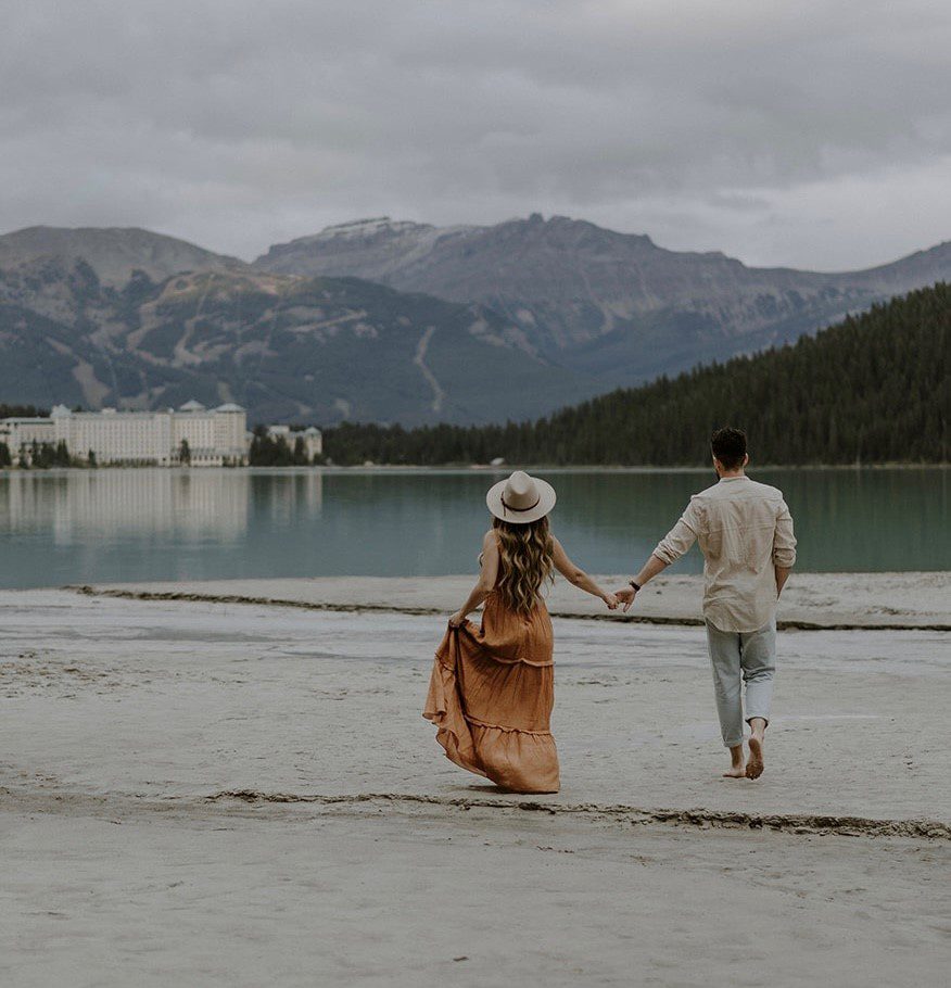 Man and Women holding hands walking towards Fairmont Chateau Lake Louise