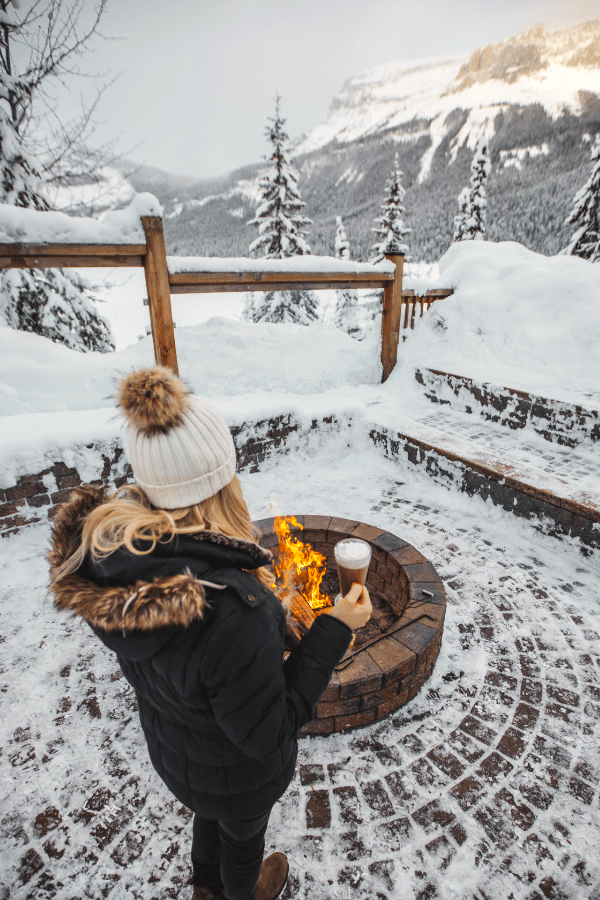 Woman sipping hot chocolate by a fire at Emerald Lake, YOHO National Park