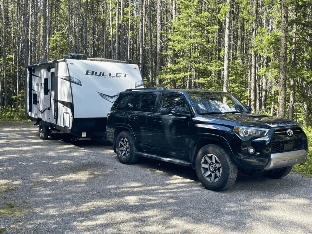 black suv with white trailer in the forest. - peter lougheed provincial park