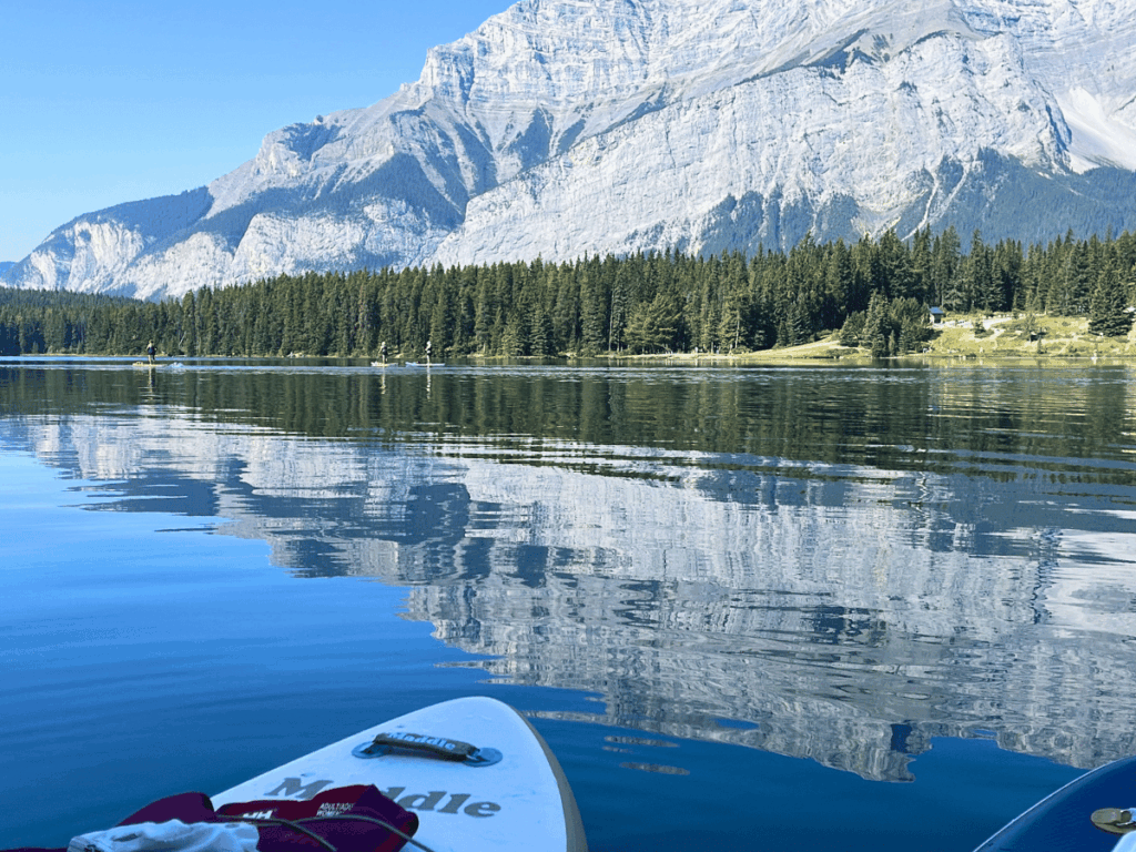 paddle board on crystal clear water with mountains - two jack lake