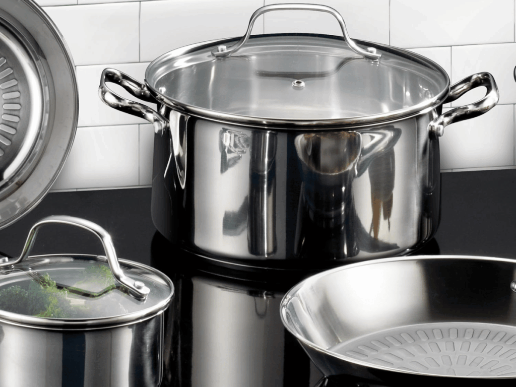 Stainless Steel Cookware on black top with white tiled backdrop