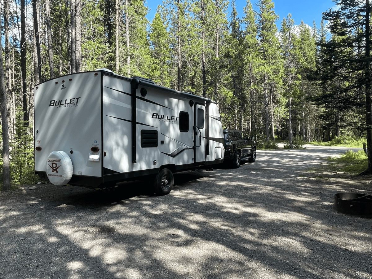 White Travel Trailer in forested RV Park 
