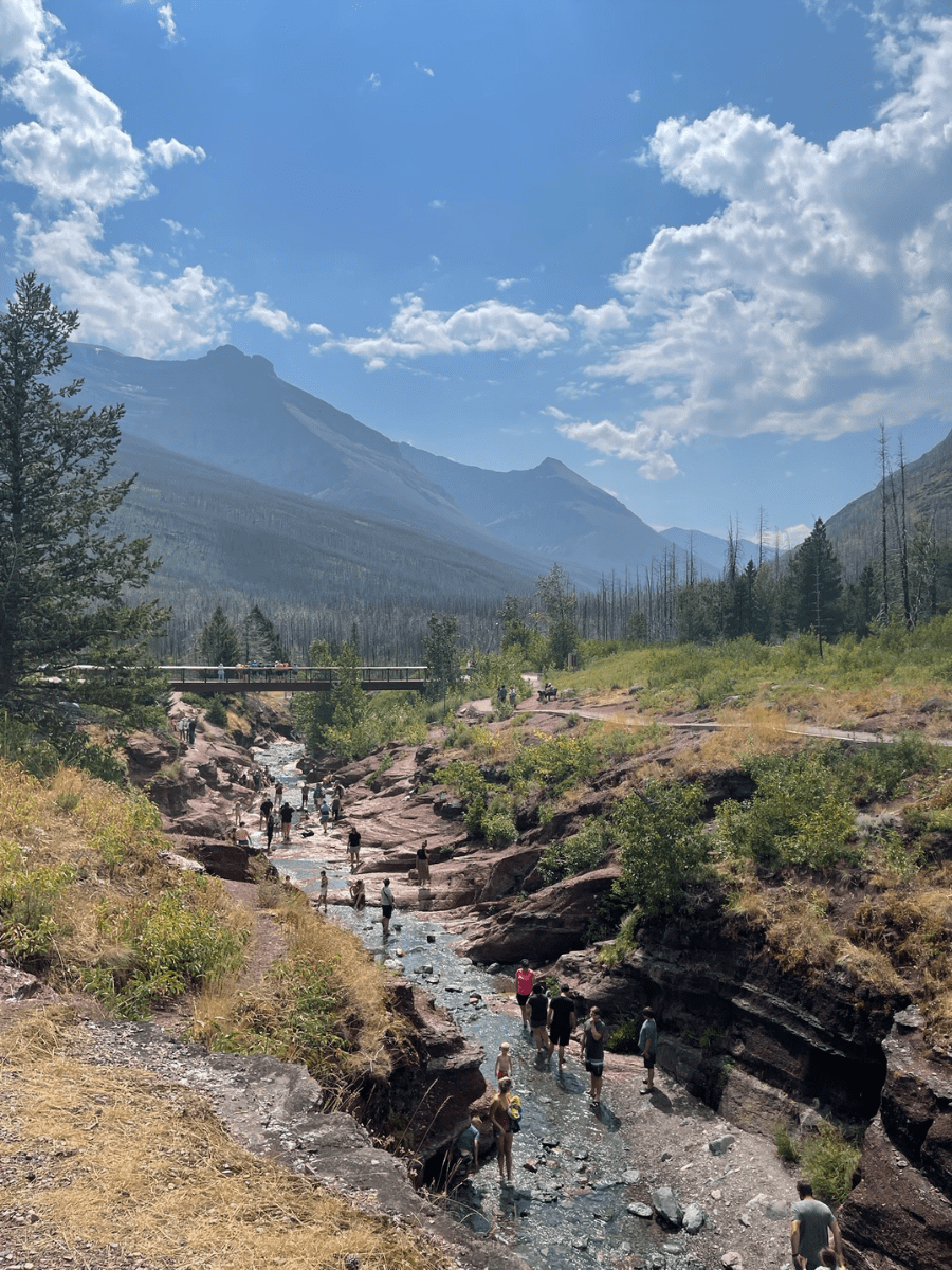 People enjoying Red Rock Canyon in Waterton National Park with hazy mountain backdrops