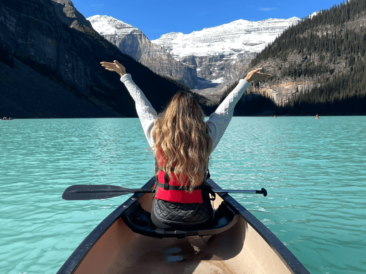 Woman canoeing on Lake Louise Banff surrounded by turquoise water and Rocky Mountains