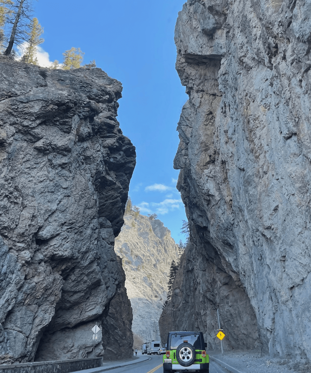 Driving through massive rock surfaces at Sinclair Canyon in Kootenay National Park