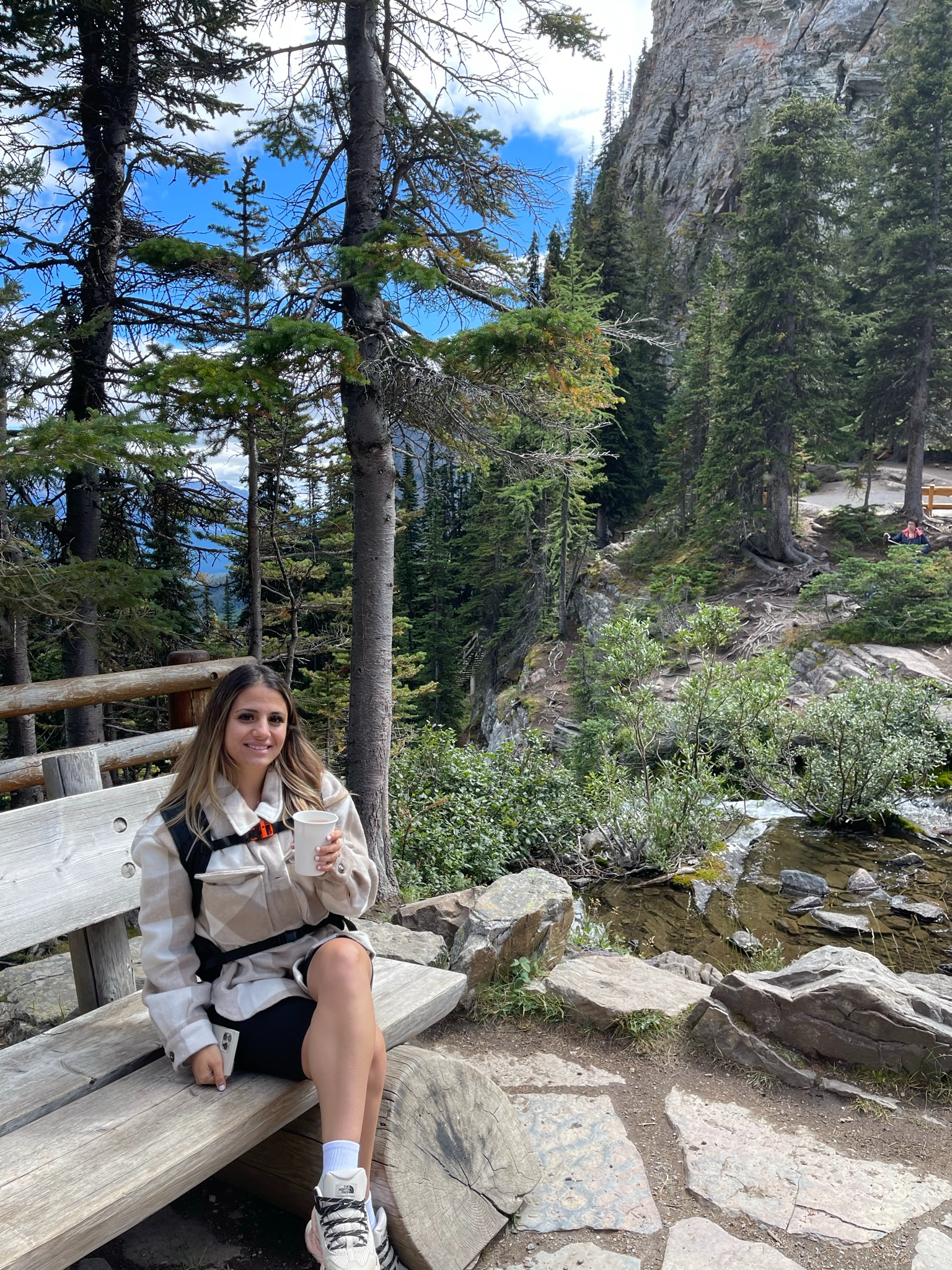 Girl sitting on a bench in the mountains drinking tea