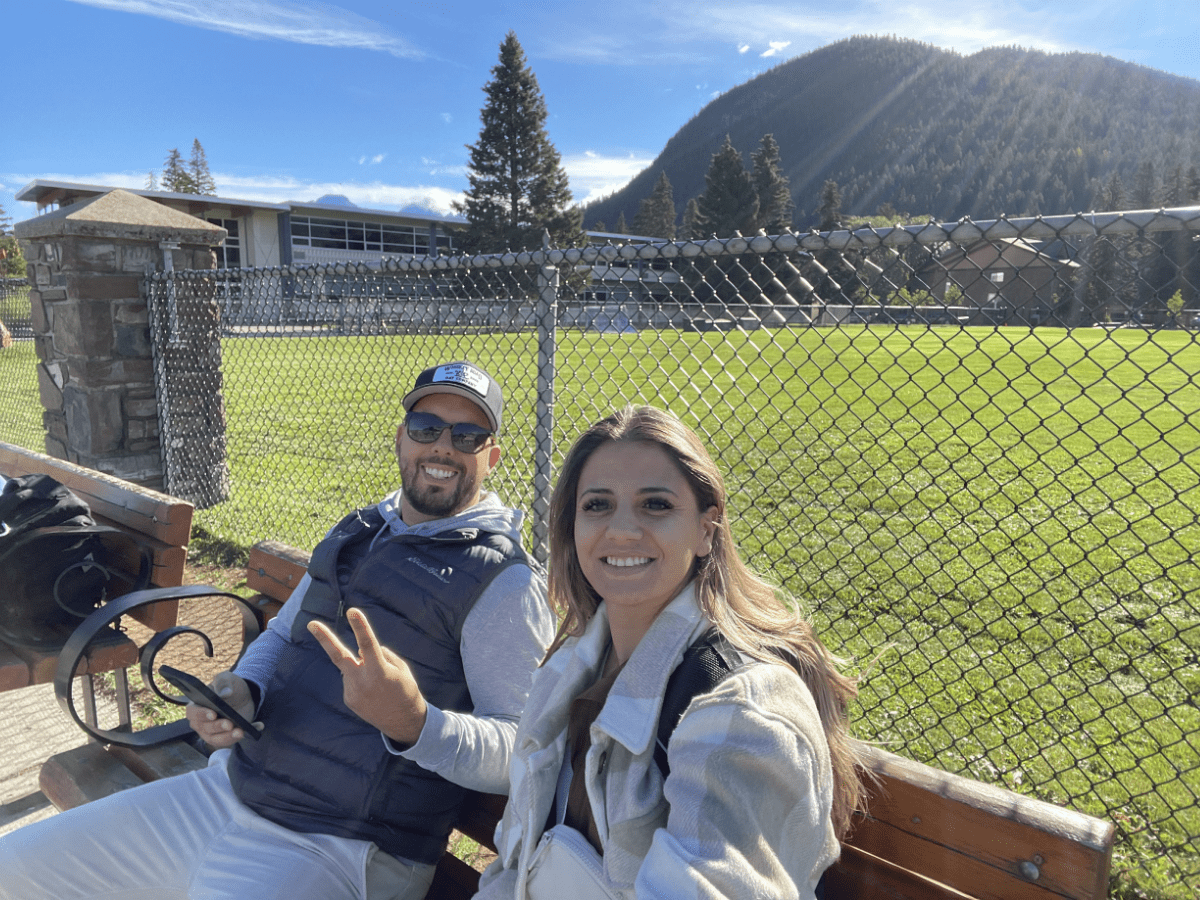 Visitors waiting for a Roam Transit bus in Banff with scenic mountain views and park surroundings.