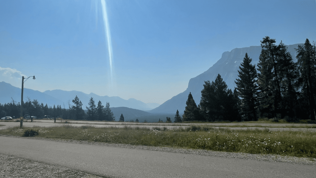 Mountain view from Tunnel Mountain Campground in Banff National Park with evergreen trees, campground roads, and a clear blue sky.