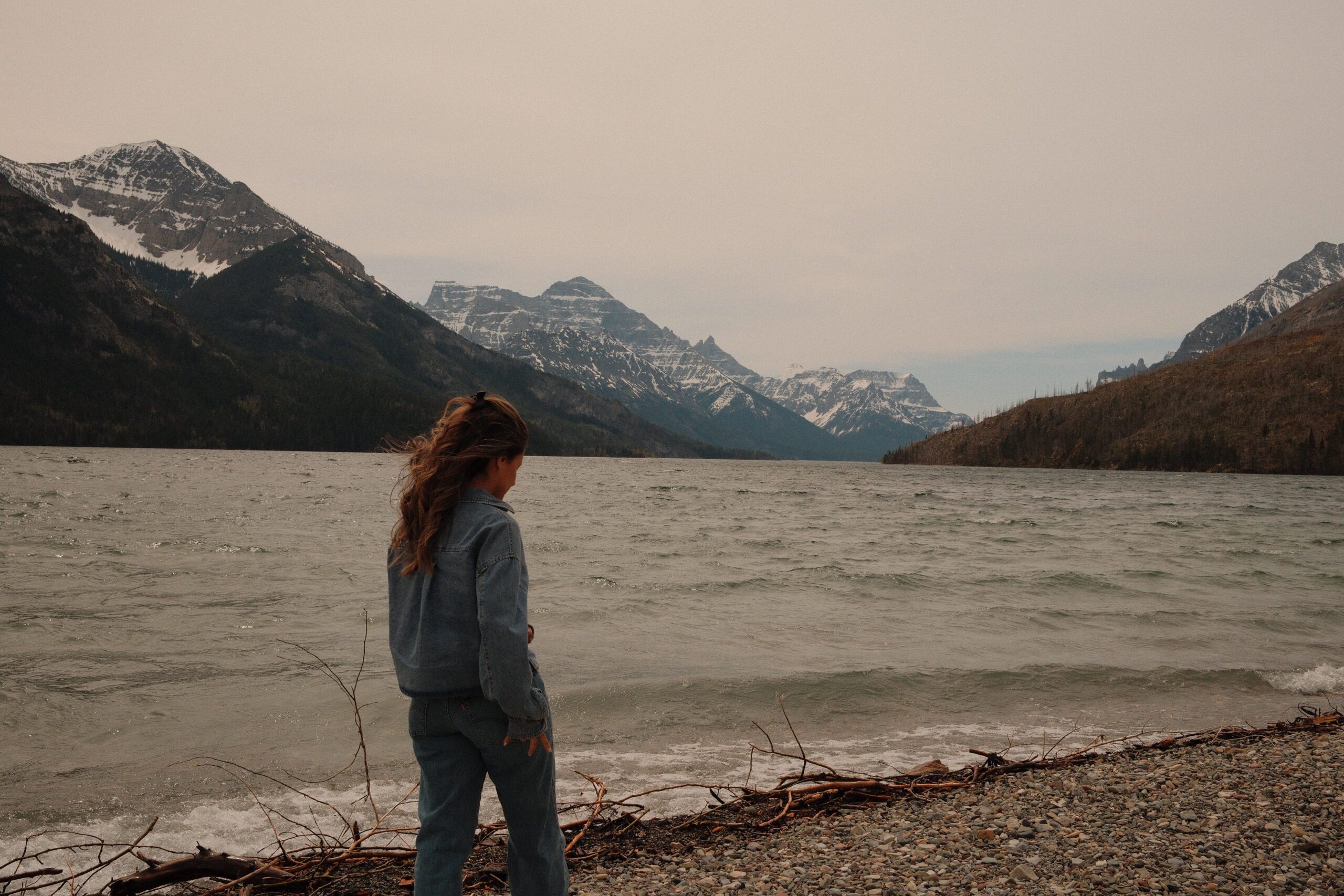 Visitor enjoying the shoreline of Upper Waterton Lake with dramatic Rocky Mountain scenery in Waterton Lakes National Park, Alberta.